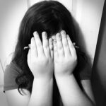 Shy girl covering her face with her hands