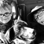 Smiling brothers in the back seat with their dog