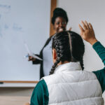 Student raising her hand in the classroom.
