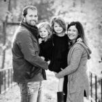 Mom and Dad holding two young daughters in a park.